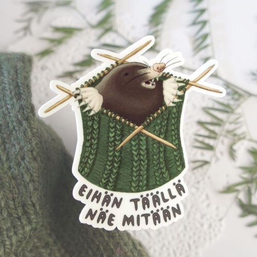 Neulonta-aiheinen tarra, jossa myyrä löytää itsensä keskeneräisen villasukan sisältä.