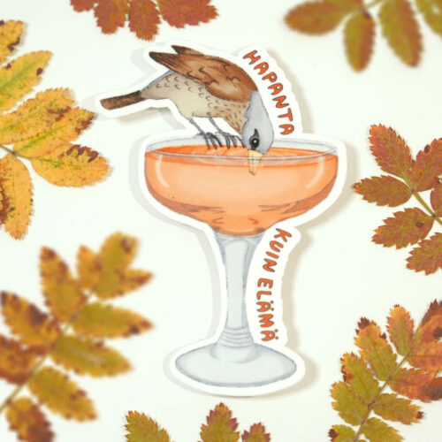 Lintuaiheinen tarra, jossa rastas juo pihlajanmarjaviiniä, joka on hapanta kuin elämä.