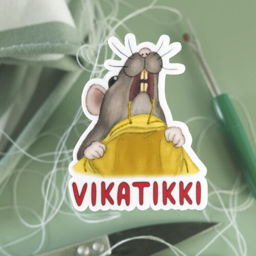 Ompeluaiheinen tarra, jossa rotta ratkoo hampaillaan pieleen mennyttä saumaa.